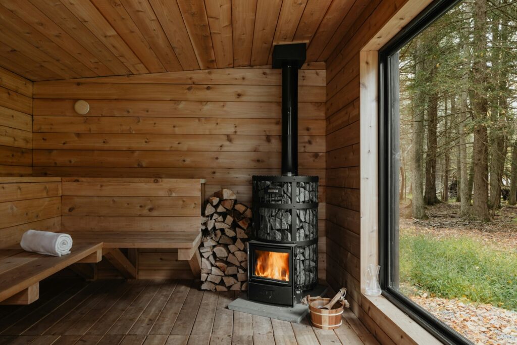 eine Holzsauna von innen mit kamin und Fenster mit Ausblick auf den Wald im wohin Kurzurlaub mit Kindern