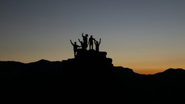 Umrisse einer Familie auf einem Hügel in der Dämmerung im Urlaub mit erwachsenen Kindern