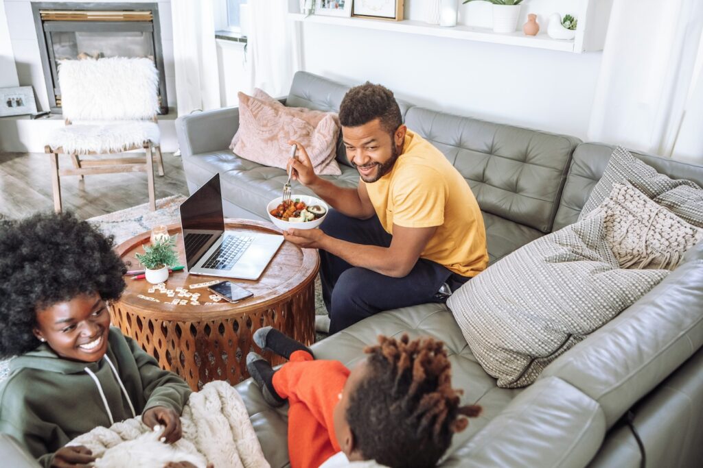 Tipps Familienurlaub: Planung. Eine Familie die auf dem Sofa zusammen sitzt.